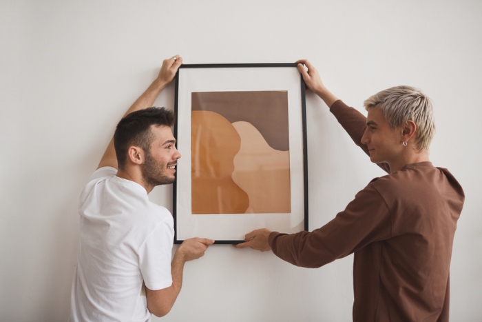 two men hanging picture on wall